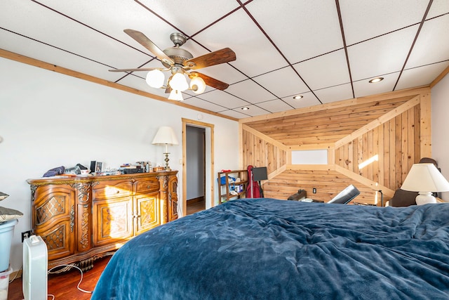 bedroom featuring hardwood / wood-style flooring, ceiling fan, crown molding, and wood walls