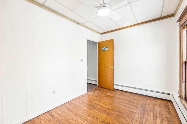 spare room featuring a baseboard heating unit, ceiling fan, and hardwood / wood-style floors