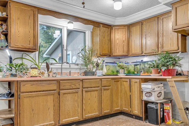 kitchen with a textured ceiling, crown molding, and sink