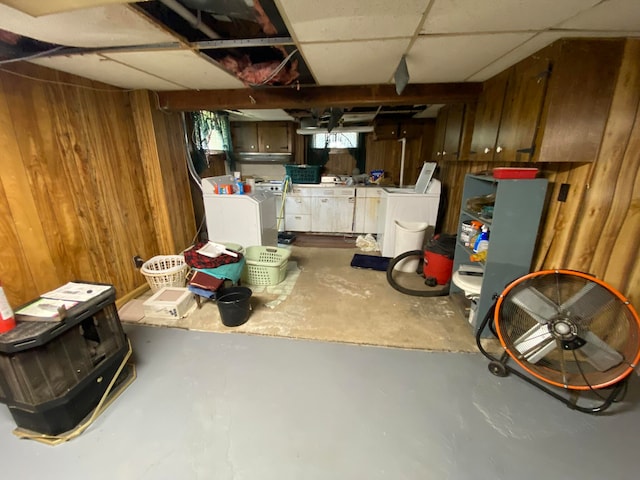 basement with wood walls, ceiling fan, and independent washer and dryer