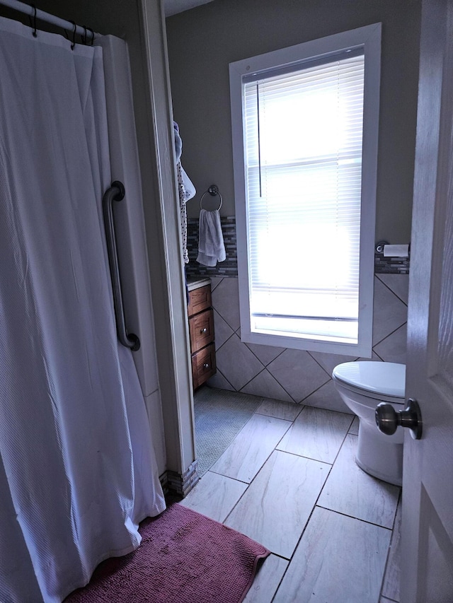 bathroom with toilet and tile walls