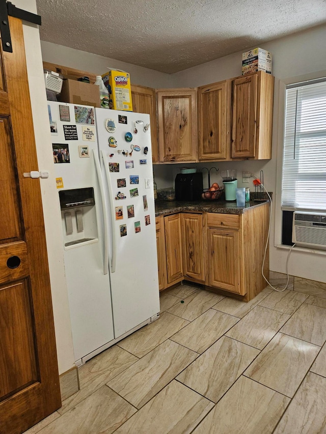 kitchen featuring cooling unit, white fridge with ice dispenser, and a textured ceiling