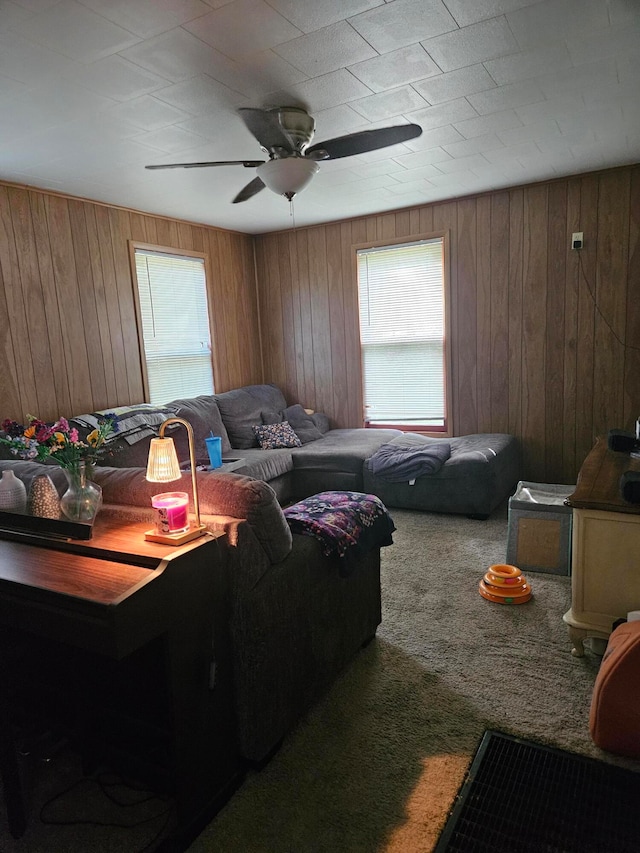 carpeted living room featuring ceiling fan and wood walls