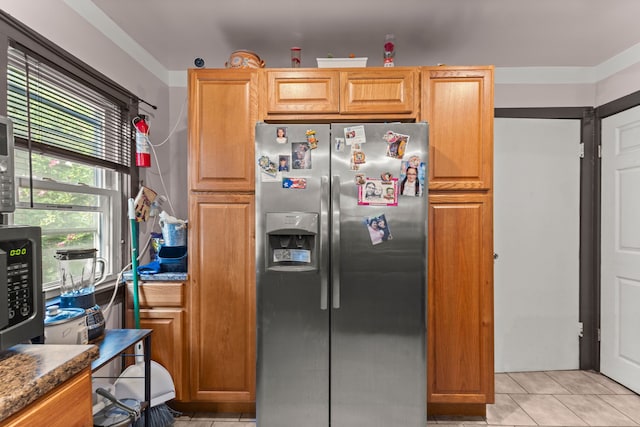 kitchen with stainless steel fridge, light tile patterned floors, and dark stone counters