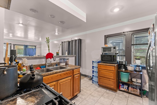 kitchen featuring a wealth of natural light, sink, light tile patterned floors, and appliances with stainless steel finishes