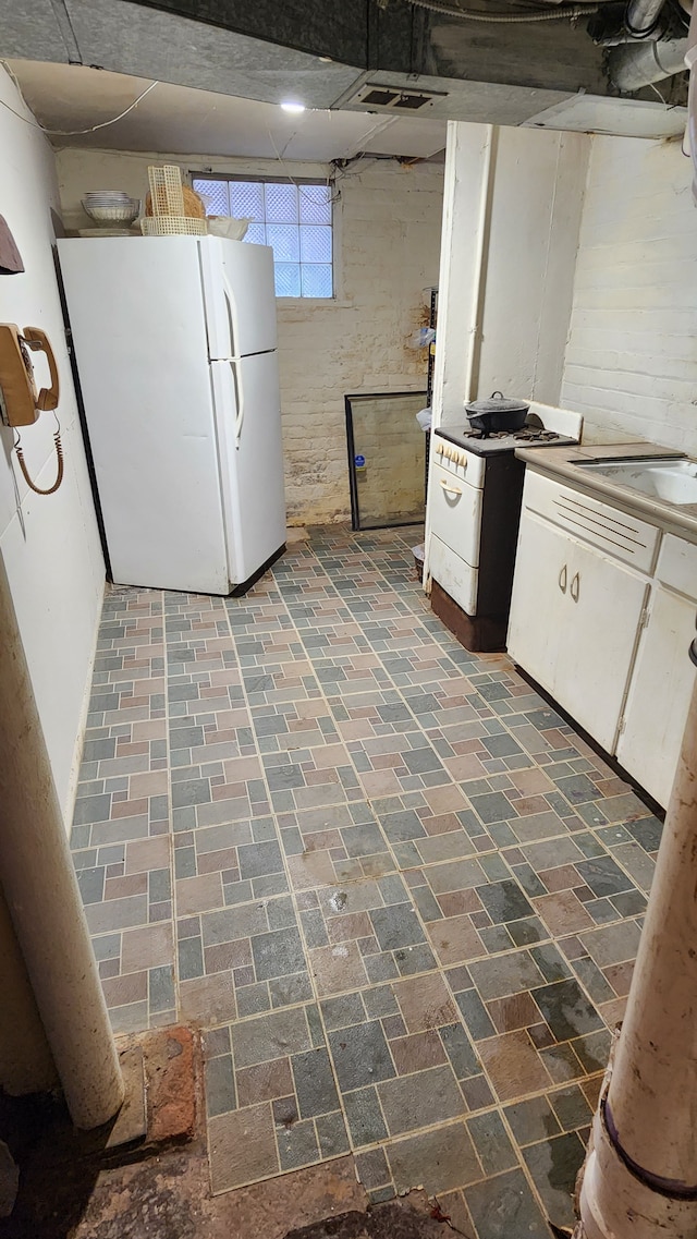 kitchen featuring white cabinets, white refrigerator, and sink