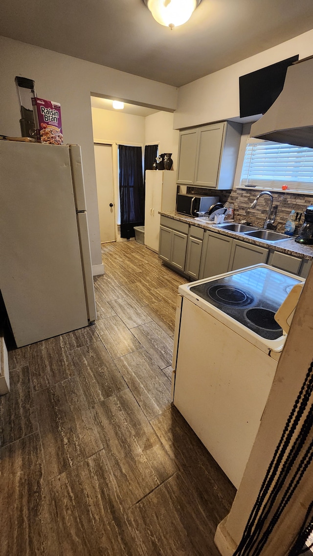 kitchen featuring white appliances, exhaust hood, sink, decorative backsplash, and dark hardwood / wood-style flooring