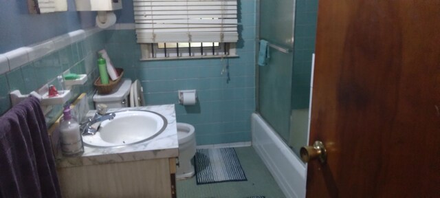 full bathroom featuring tile patterned floors, vanity, tile walls, enclosed tub / shower combo, and toilet