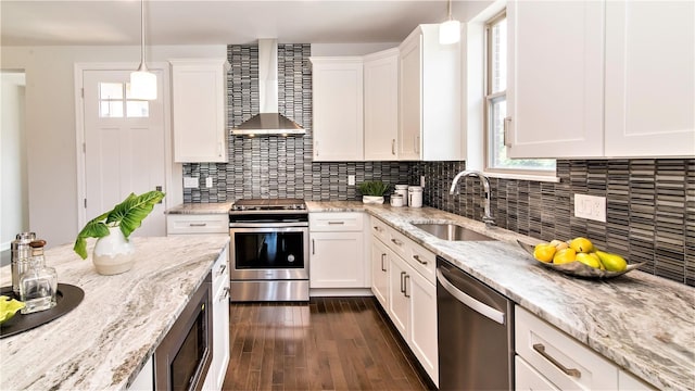 kitchen with white cabinetry, stainless steel appliances, wall chimney range hood, plenty of natural light, and pendant lighting