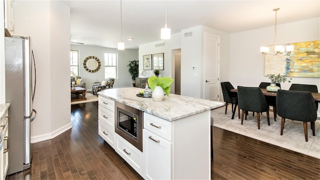 kitchen featuring pendant lighting, white cabinets, light stone counters, appliances with stainless steel finishes, and dark hardwood / wood-style flooring