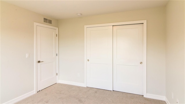 unfurnished bedroom featuring light carpet and a closet