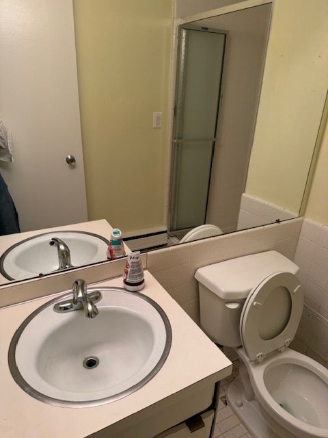 bathroom featuring tile patterned floors, toilet, sink, and tile walls