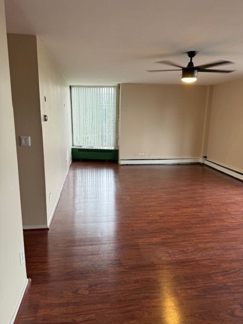 unfurnished room with ceiling fan, dark wood-type flooring, and a baseboard radiator