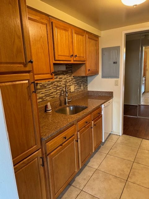 kitchen featuring decorative backsplash, dark stone counters, sink, light tile patterned floors, and dishwasher