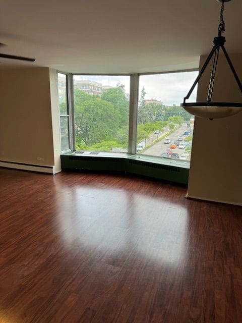 unfurnished room featuring dark hardwood / wood-style floors and baseboard heating