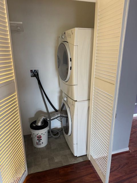 laundry room featuring dark hardwood / wood-style flooring and stacked washer / drying machine