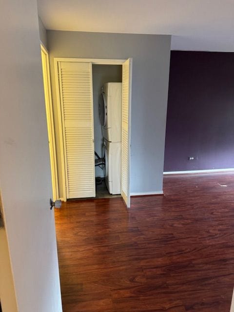 unfurnished bedroom with a closet, dark hardwood / wood-style floors, and stacked washer / dryer