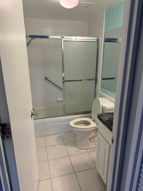 full bathroom with shower / bath combination with glass door, vanity, toilet, and tile patterned flooring