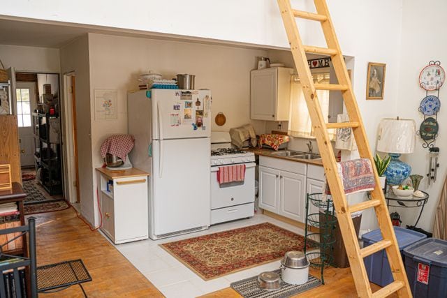 kitchen featuring white cabinets, light wood-type flooring, white appliances, and sink