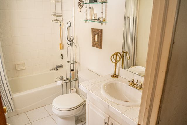 full bathroom with tile patterned flooring, tiled shower / bath combo, toilet, and vanity