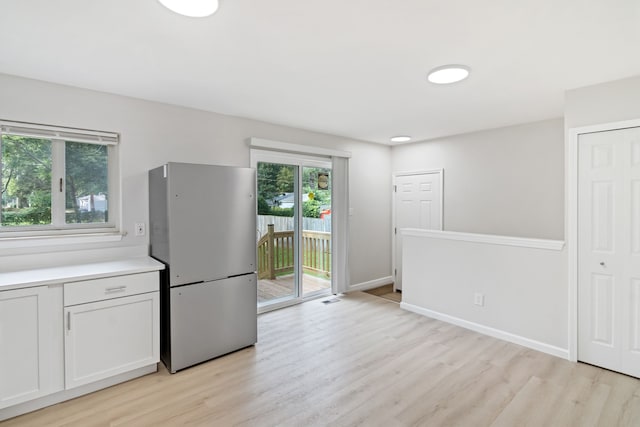 kitchen with white cabinetry, stainless steel fridge, and light wood-type flooring