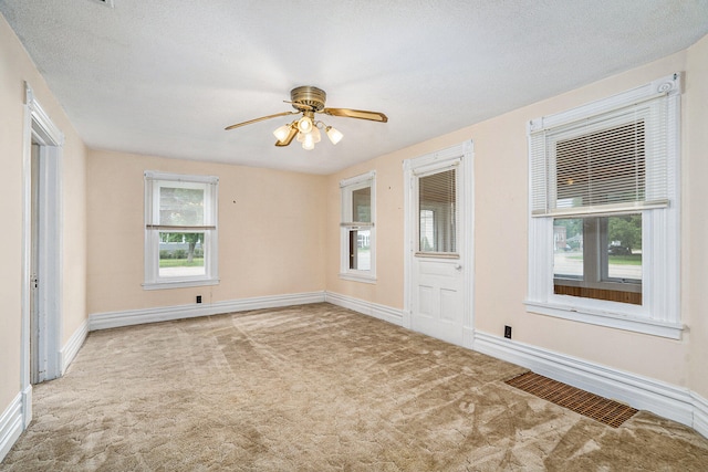 carpeted empty room with ceiling fan, a healthy amount of sunlight, and a textured ceiling