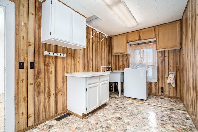 laundry room with wooden walls, cabinets, and washer / dryer