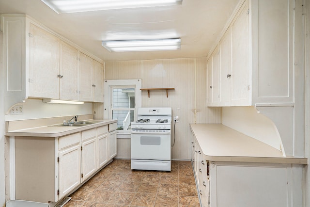 kitchen featuring white gas range, white cabinetry, and sink