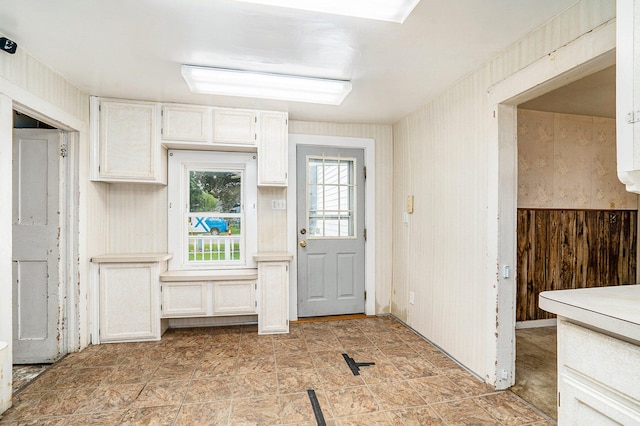 kitchen with white cabinetry and wood walls