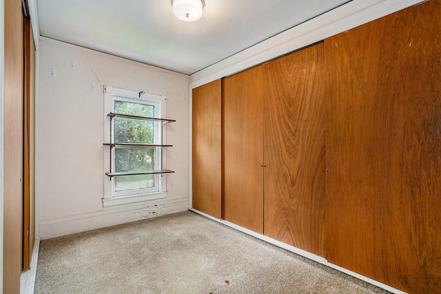 unfurnished bedroom with light colored carpet and a closet