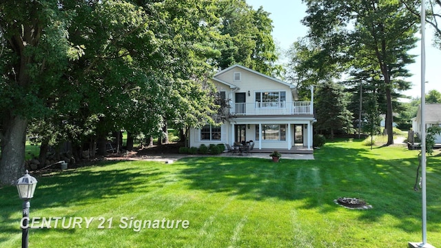 view of front of property featuring a balcony, a patio, and a front yard