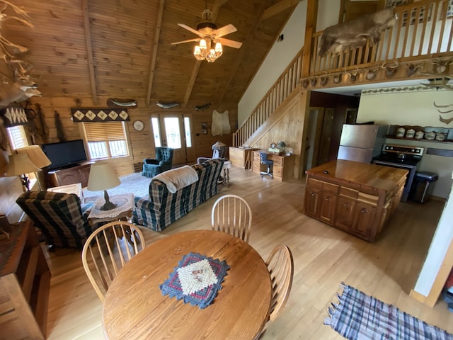 dining area with ceiling fan, beam ceiling, wooden walls, and light hardwood / wood-style flooring