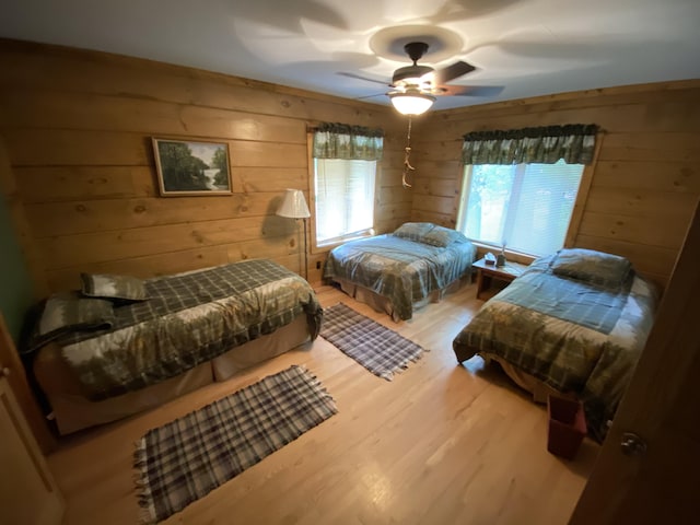 bedroom featuring ceiling fan, wood walls, and hardwood / wood-style flooring