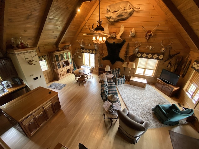 living room featuring wooden walls, ceiling fan, beamed ceiling, light hardwood / wood-style floors, and wood ceiling