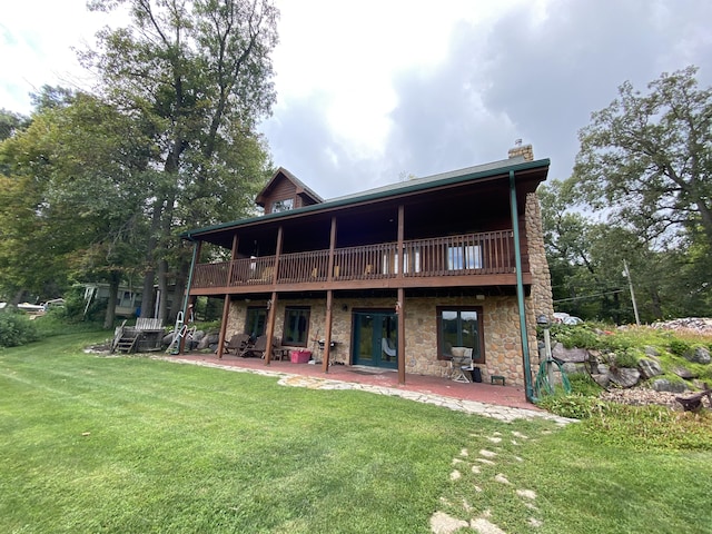 rear view of house with a wooden deck, a yard, and a patio