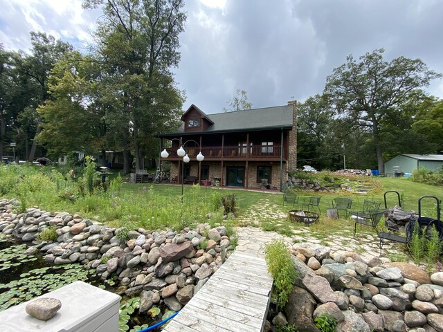 rear view of house with a fire pit, a deck, and a lawn