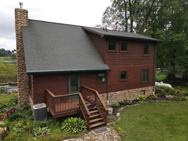 rear view of property featuring a yard, a deck, and central air condition unit