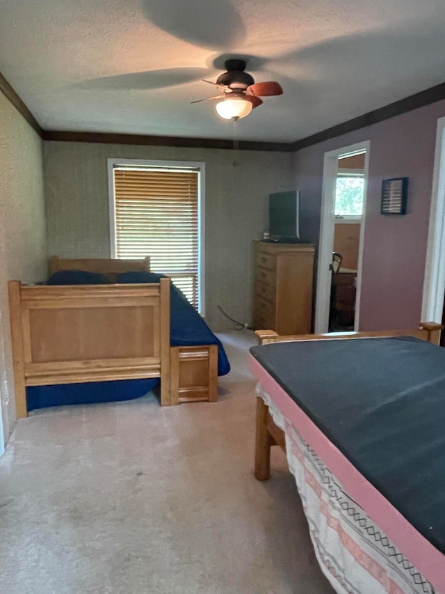 carpeted bedroom with a textured ceiling, ceiling fan, and ornamental molding