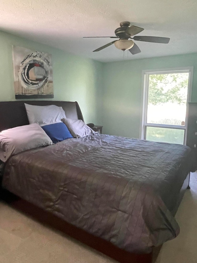 bedroom featuring carpet flooring, ceiling fan, and a textured ceiling