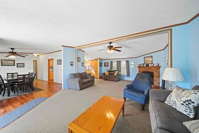 living room featuring ceiling fan, ornamental molding, a textured ceiling, and hardwood / wood-style flooring