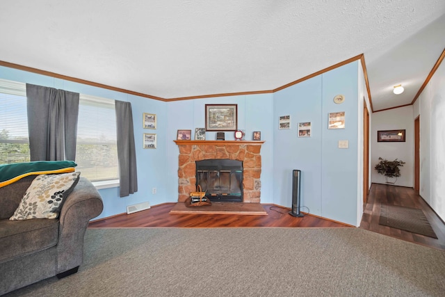 living room featuring lofted ceiling, crown molding, hardwood / wood-style flooring, a fireplace, and a textured ceiling