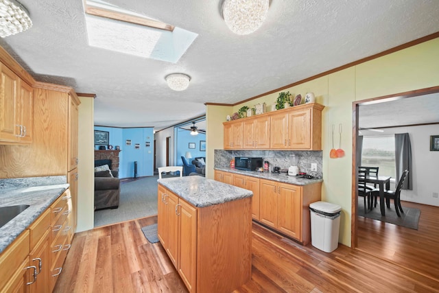 kitchen featuring light stone counters, a kitchen island, light hardwood / wood-style floors, and a textured ceiling