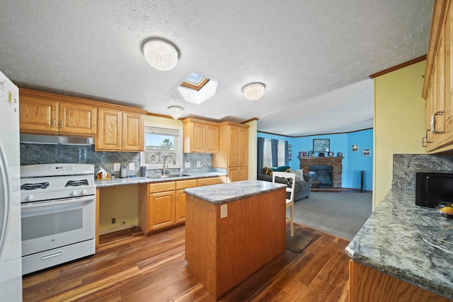 kitchen with dark hardwood / wood-style floors, a stone fireplace, decorative backsplash, and white gas range oven