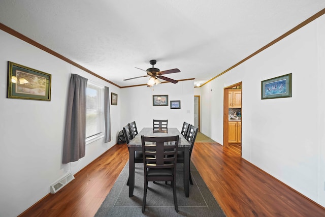 dining room featuring dark hardwood / wood-style flooring, ceiling fan, and crown molding