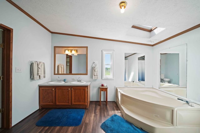 bathroom featuring ornamental molding, vanity, a textured ceiling, lofted ceiling with skylight, and hardwood / wood-style floors