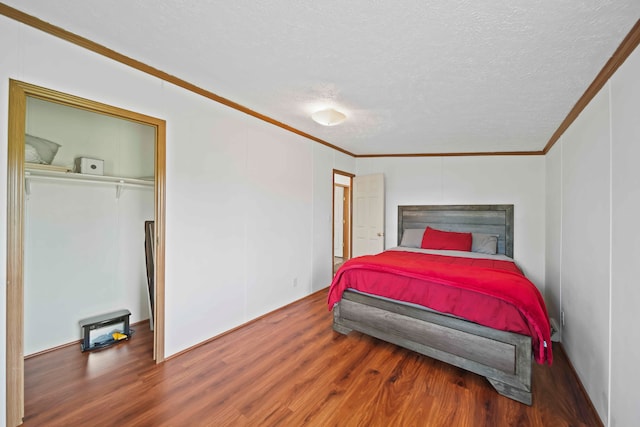 bedroom featuring hardwood / wood-style floors, a textured ceiling, a closet, and ornamental molding