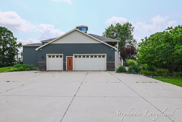 7300 Packer Dr NE, Belmont, MI 49306 - view of side of property featuring stone siding, an attached garage, and driveway