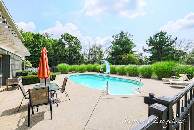 view of swimming pool with a diving board, a patio area, and a water slide