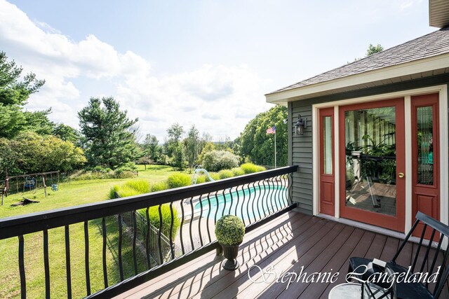 7300 Packer Dr NE, Belmont, MI 49306 - wooden deck featuring an outdoor pool, a yard, view of wooded area, and a playground