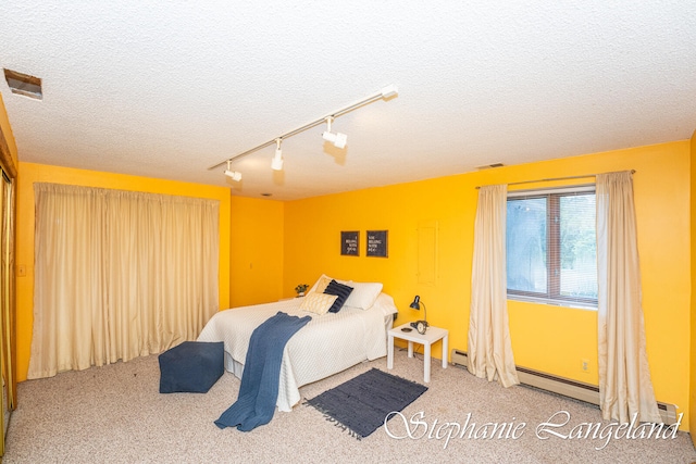 bedroom featuring a textured ceiling, carpet floors, and track lighting